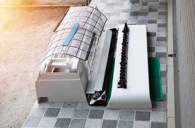Disassembled AC indoor unit showing filter, casing, and blower parts